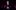 ©J-Lee_9-NTConnections24_266 A person stands on a platform with hands cupped around their mouth, while another sits below them with a stern expression. They are illuminated by a spotlight on a dark stage. Several other individuals stand in the background, partially obscured by shadows.