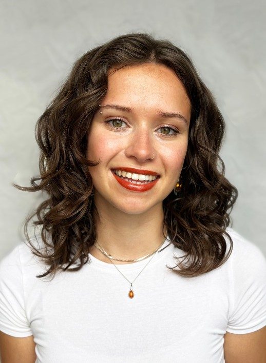 Jodie-Yates-headshot-JodieYates-518x708 A photograph of a young person with long brown, wavy hair and wearing red lipstick