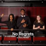 Three individuals stand in a theater setting with red and black decor. The person on the left has a raised fist, the middle person is smiling, and the person on the right appears thoughtful. The text reads 
