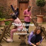 Four individuals are interacting with wooden chairs in an outdoor setting with a brick wall. The poster is for the 