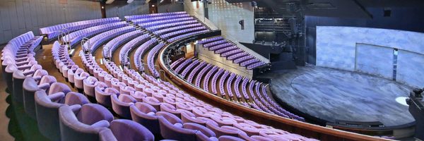 Olivier-Theatre-auditorium-seating-standard-masthead Inside the Olivier Theatre auditorium, with purple cloth-covered seats in a fan shape, descending to a circular stage.