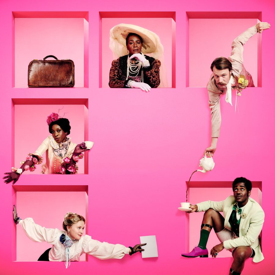The-Importance-of-Being-Earnest-National-Theatre-artwork-2000x1000 Five people in colorful vintage attire are framed within pink square cutouts against a bright pink background. They each pose differently, showcasing their unique outfits, which feature eccentric accessories like a large hat, pearls, and floral embellishments.