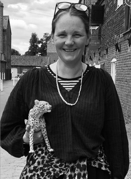 Tiffany-FraserSteele-headshot-OliviaSteward-518x708 A black and white photo of a person smiling wearing a black cardigan and carrying a leopard toy